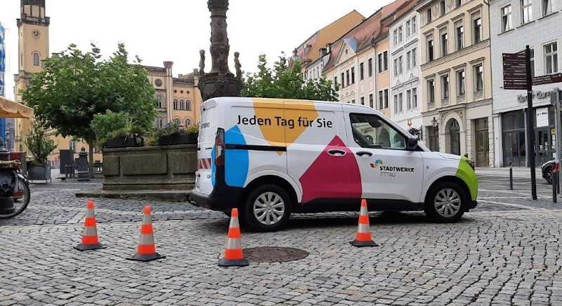 Stadtwerke Zittau Caddy vor einem Brunnen am Zittauer Marktplatz mit 4 Warnkegeln