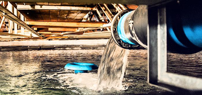 Wasser gelangt aus einem Rohr in ein Becken